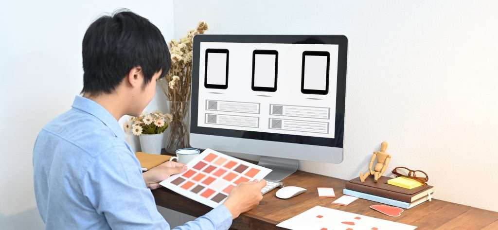 A graphic designer is selecting a color while sitting in front of a computer, wix vs jimdo vs wordpress, wix vs wordpress